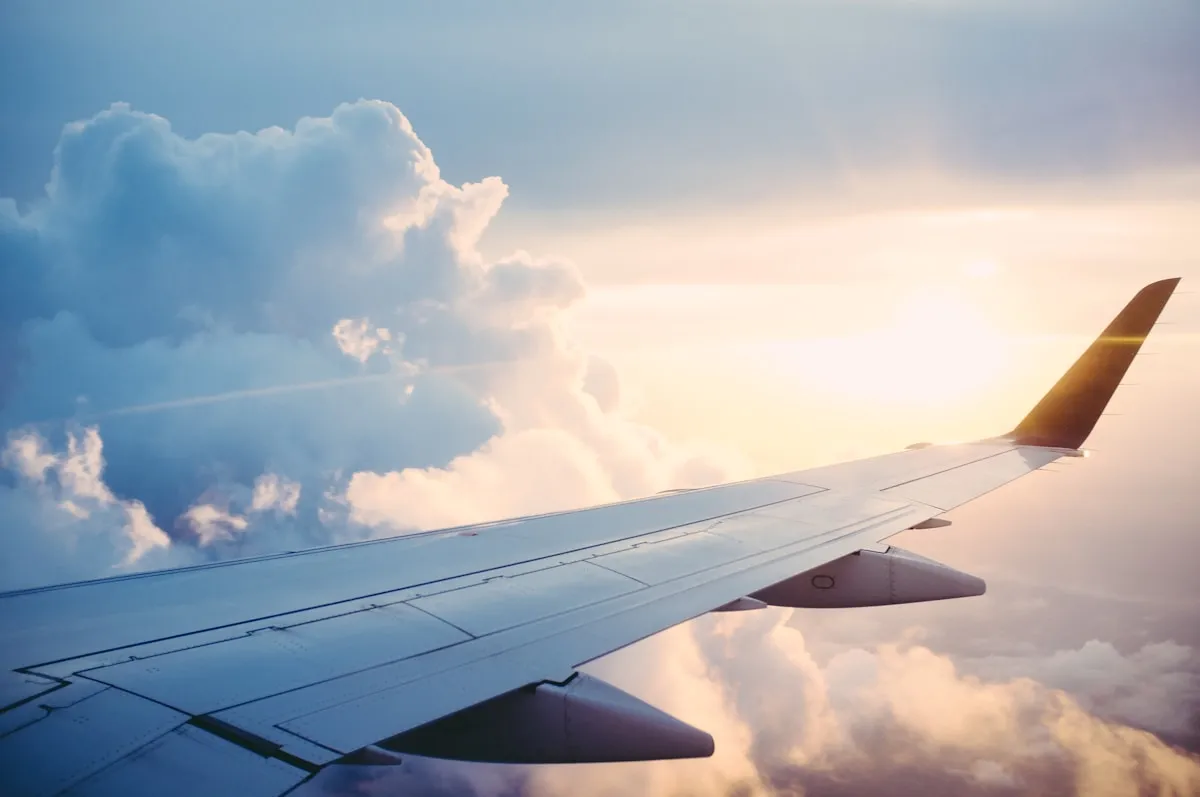 Airplane wing view above clouds at sunset